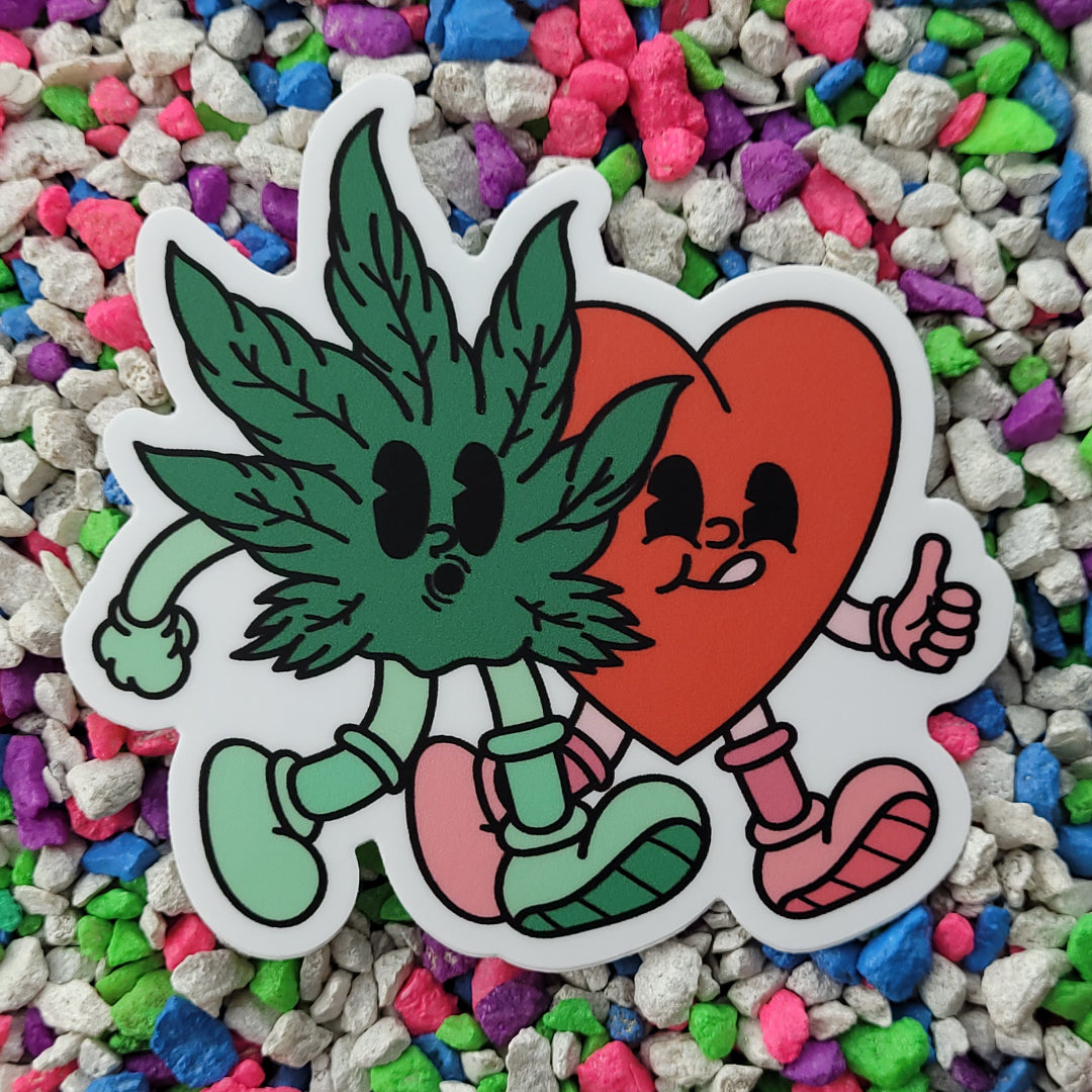 A vinyl sticker featuring a rubber hose style cartoon cannabis leaf and heart walking next to each other, with the heart giving a thumb's up and the cannabis leaf whistling.