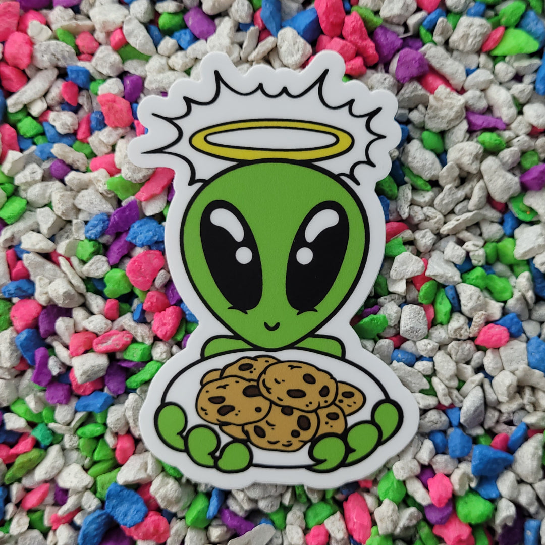 a sticker featuring a cartoon kawaii alien with a glowing halo holding out a plate of chocolate chip cookies.