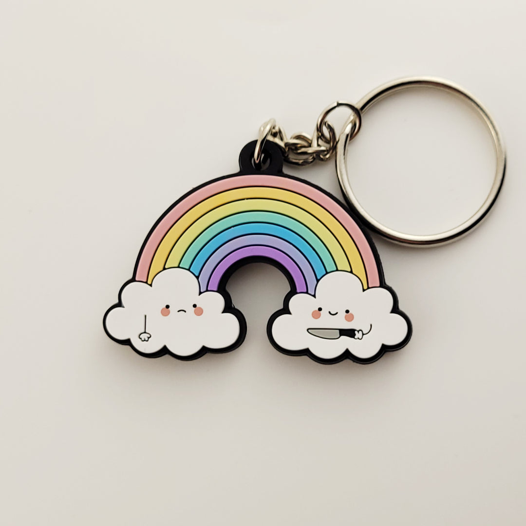 A rubber keychain with sturdy chain and ring featuring two kawaii cartoon clouds. One cloud is smiling and holding a knife, pointing it toward the other, who is frowning. This is a 2 sided keychain and the other side is mirrored.