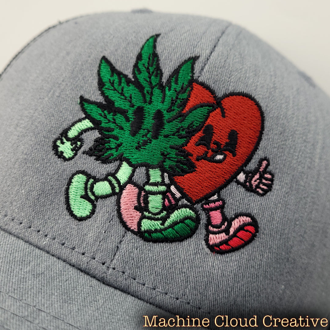 Close-up of cartoon embroidered cannabis leaf and heart on front of hat.