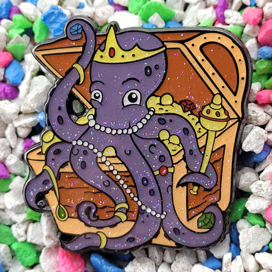 An enamel pin of an octopus sitting in a treasure chest adorning itself with gems, jewelry and accessories.